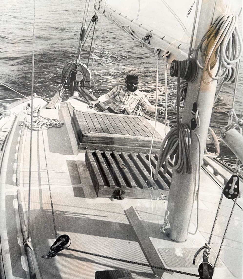 Sailboat deck with person steering vessel.