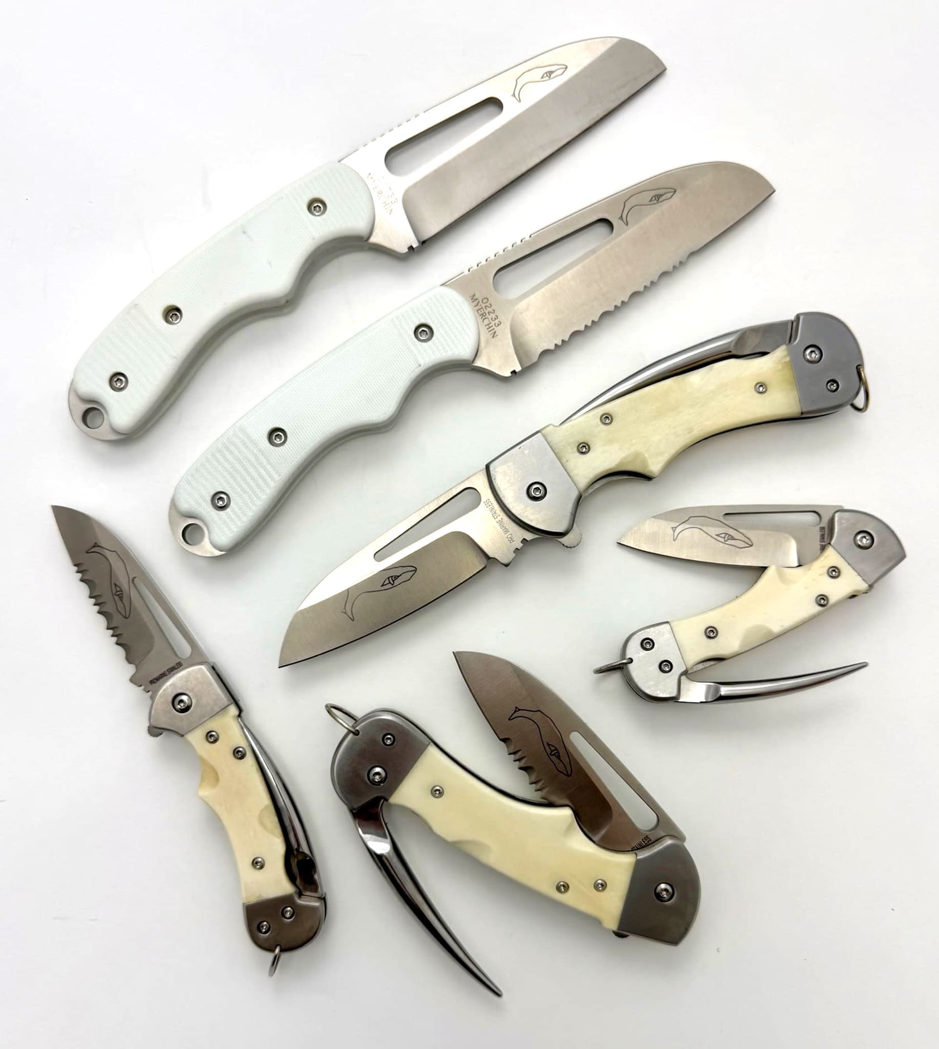 Assorted folding knives with sleek white handles.