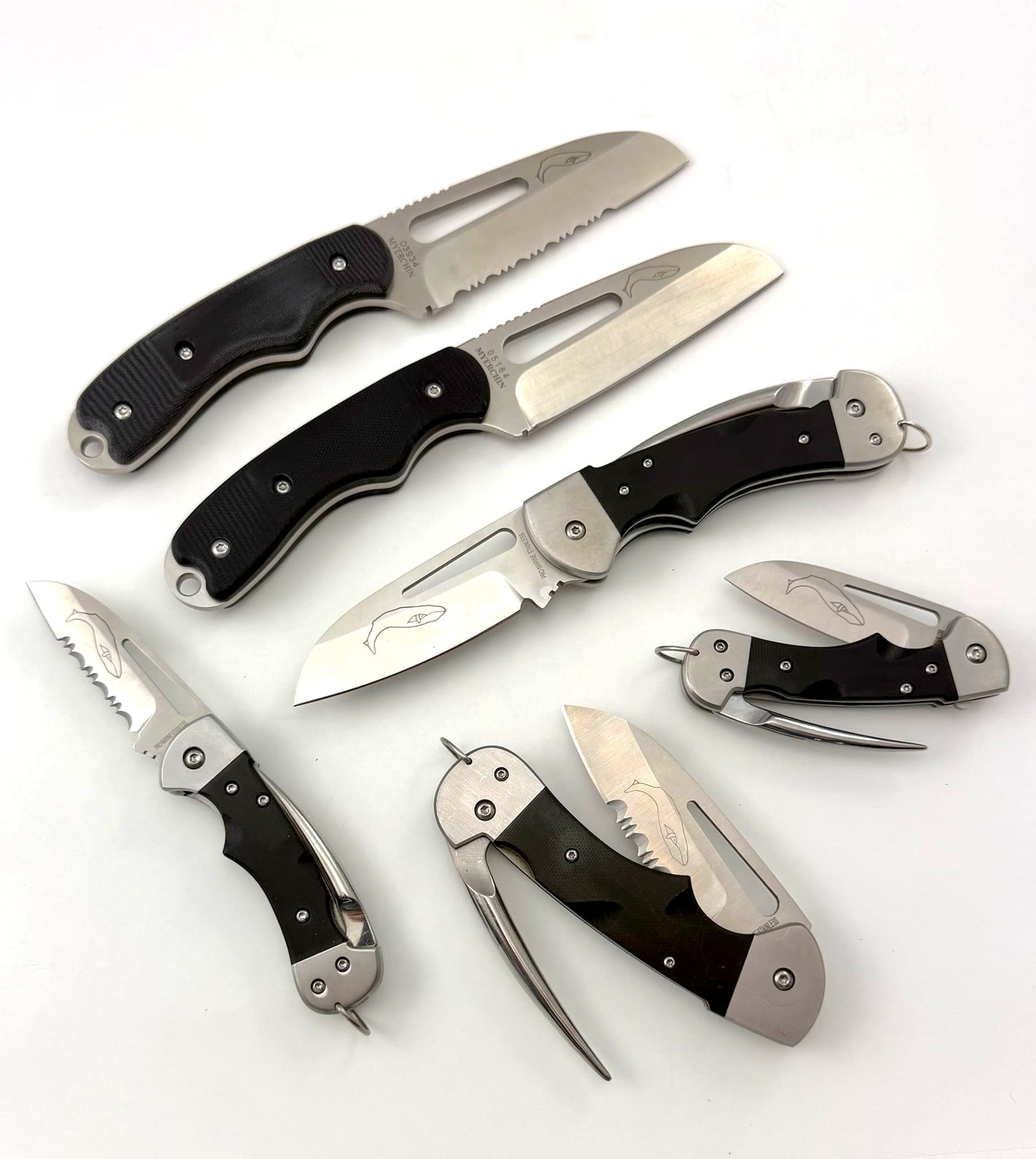 Assorted folding knives with black handles displayed.